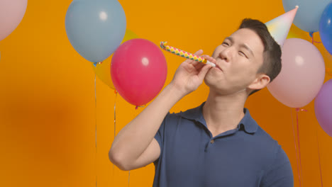 Studioporträt-Eines-Mannes-Mit-Partyhut,-Der-Geburtstag-Mit-Luftballons-Und-Partygebläse-Feiert-1
